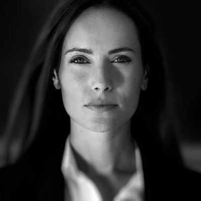 Business woman in suit outfit close up portrait, in front of a blurry background